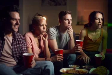 group-of-friends-with-drinks-sitting-on-sofa-at-home-watching-horror-movie-together-rbpcsvdjtjibfc10nf97swhxeqoy9a4vhhecsx9wxs
